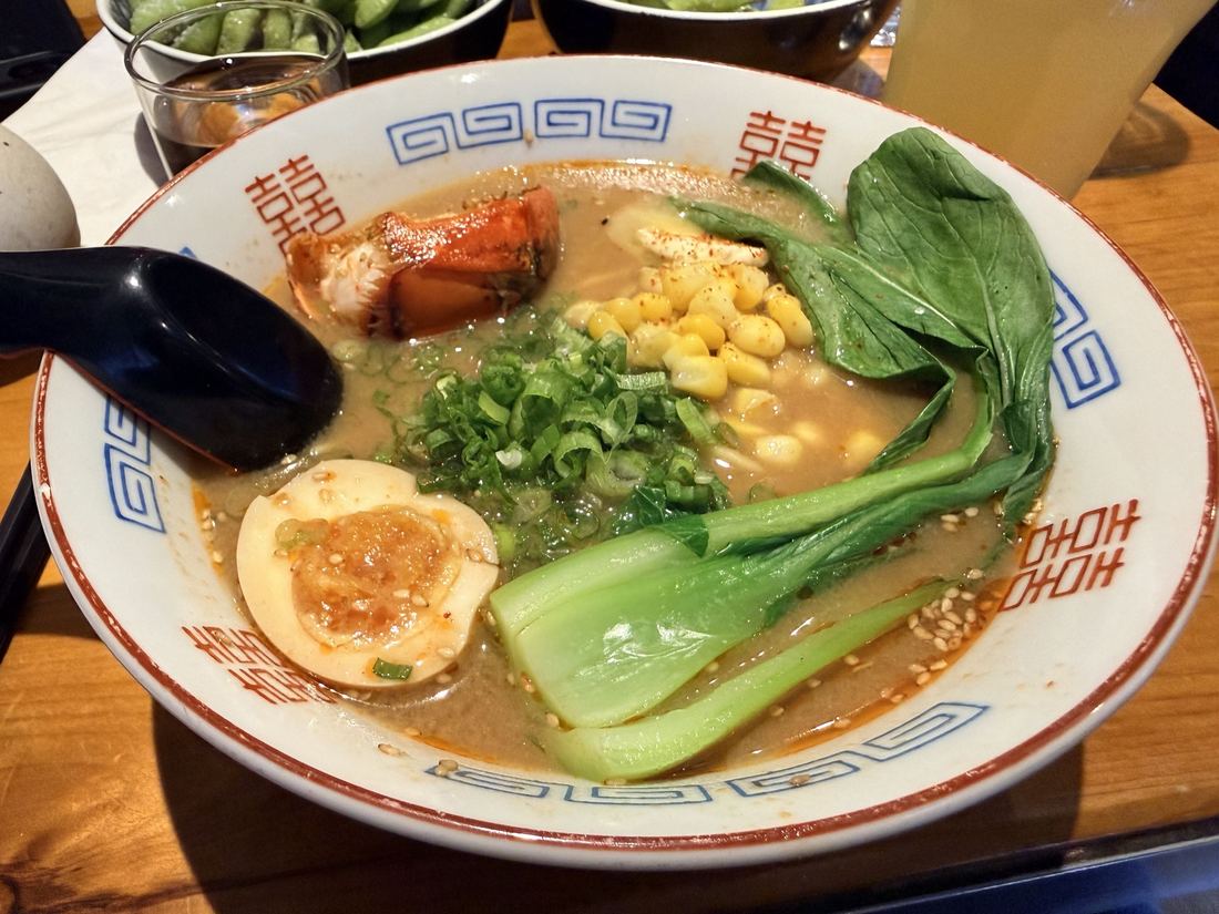 Lobster ramen, Portland. Ramen topped with a lobster tail, a soft egg, corn, bok choy and scallions, with edamame on the side.