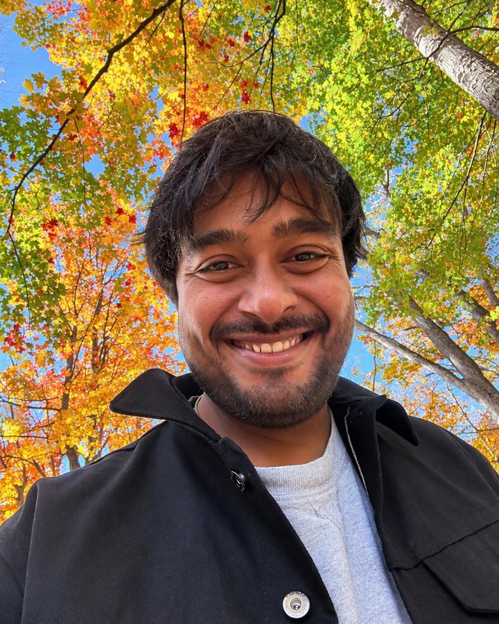 Naresh smiling under yellow and orange maples